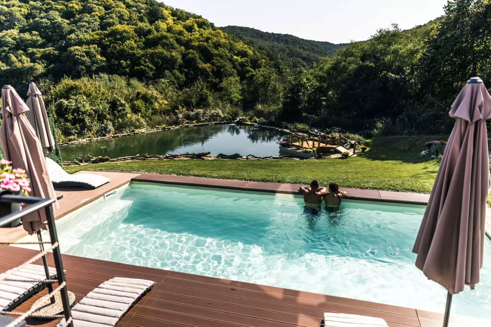 Pool und Naturteich vor Waldhuegeln